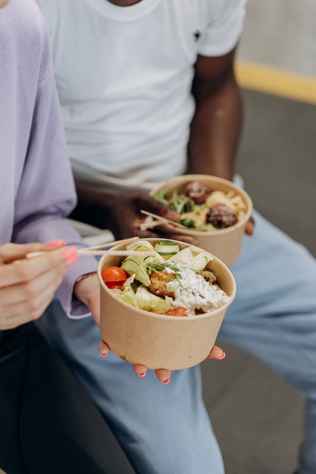 Two people holding bowls of healthy food