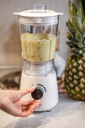 A hand operating the knob on a blender