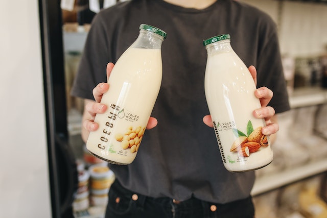 Person holding two bottles of almond and soy milk