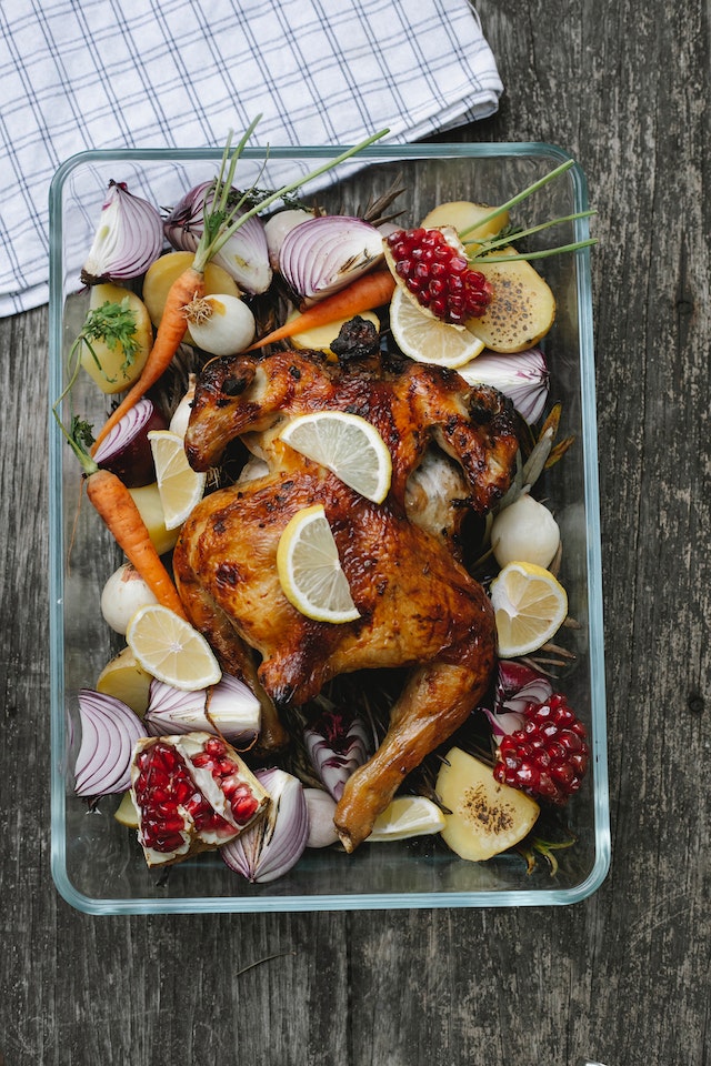 Roast chicken with an assortment f vegetables, herbs, and spices on the side