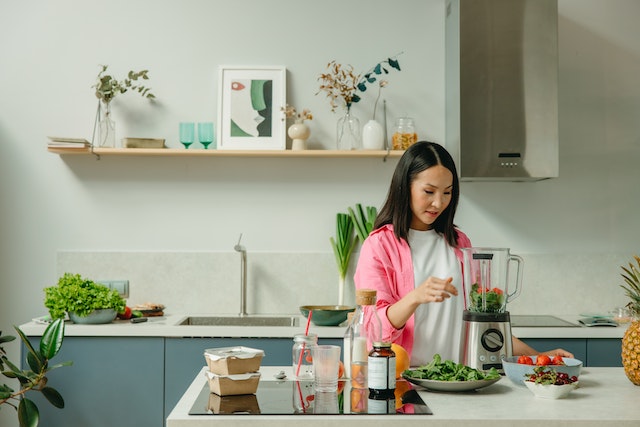 Woman adding vegetables inside a blender