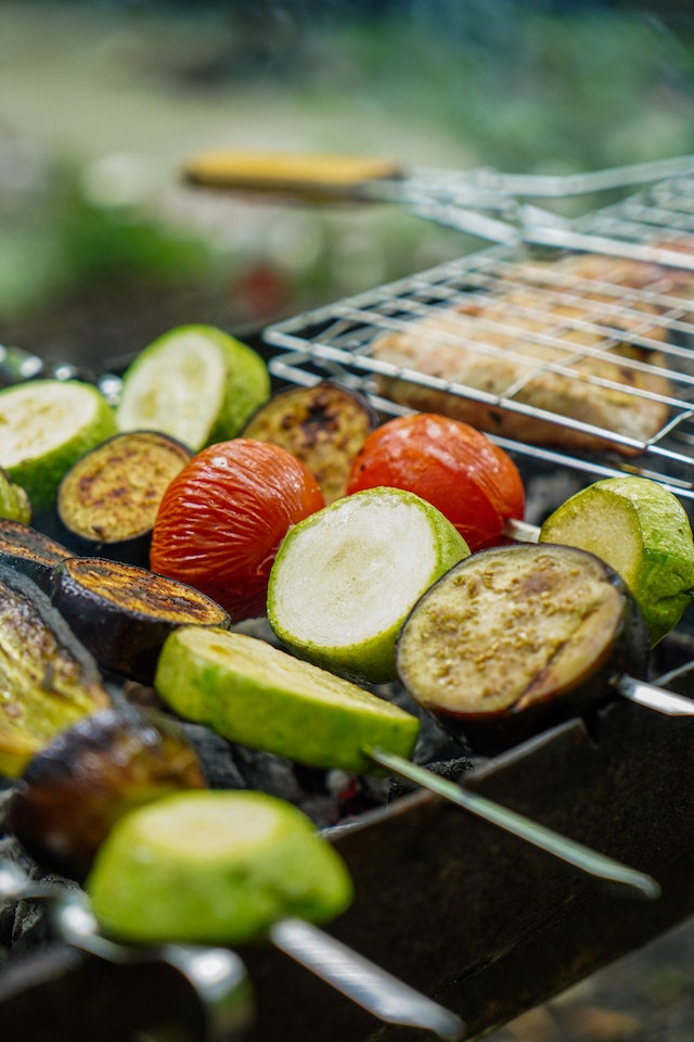 Vegetables on skewers cooking on a grill