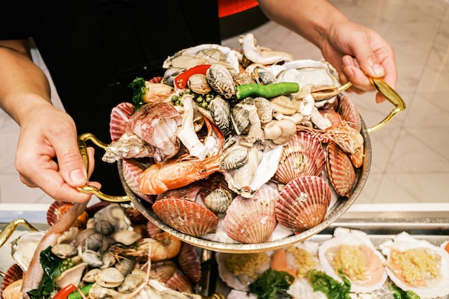 A person holding a pot filled with a variety of seafood