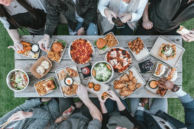 A group of friends sharing a table laid out with assorted fast food staples