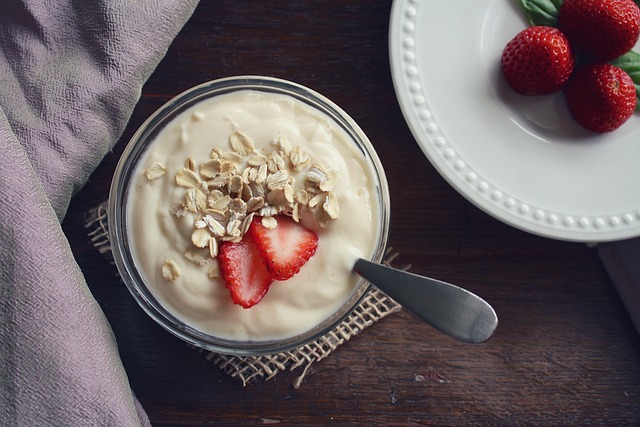 A bowl of yogurt  topped with strawberry slices and oats