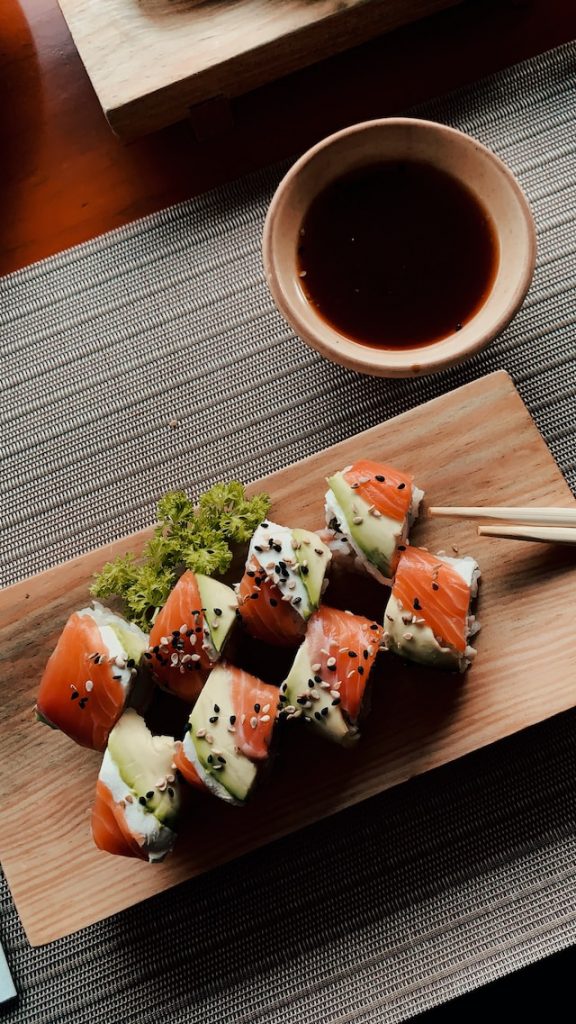 Sushi served on a wooden plate with dipping sauce on the side