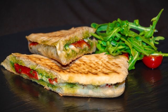 Grilled panini slices with greens and cherry tomatoes on the side