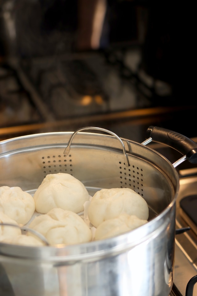 White buns cooking inside a steamer