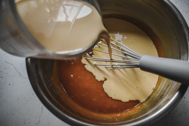 Milk being poured into a bowl of whisked eggs