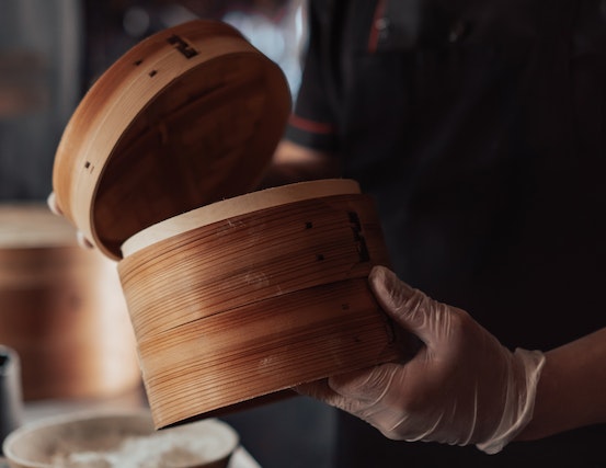 Person holding a bamboo steamer
