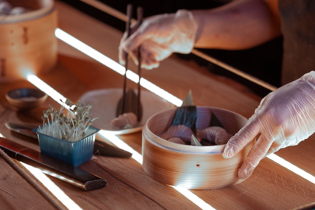 Person taking dumplings out of a bamboo steamer