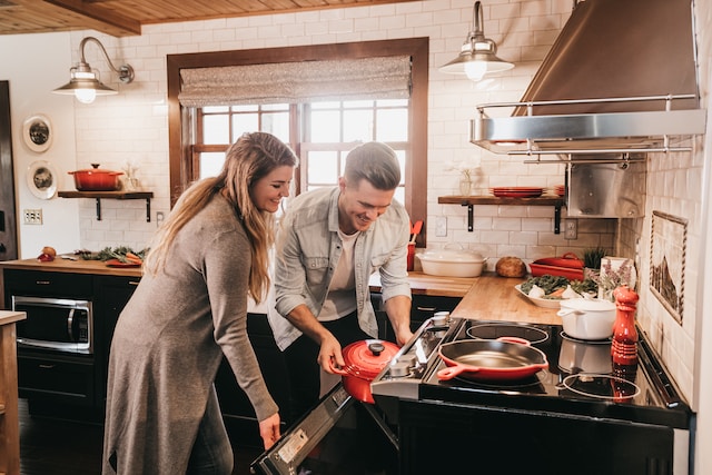 Couple taking out a red pan from the oven