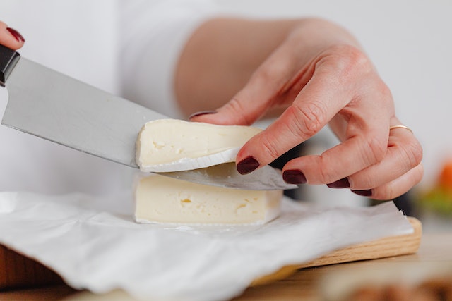 Person slicing a piece of cheese