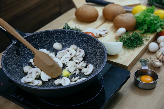 Person sautéing mushrooms in a pan with melted butter