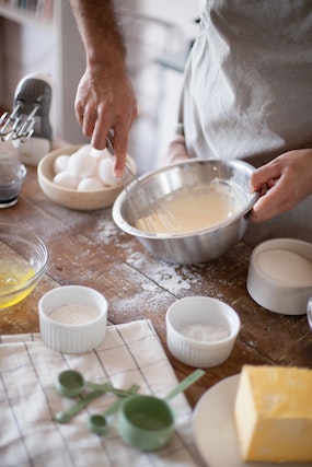 Person whisking eggs in an aluminum mixing bowl