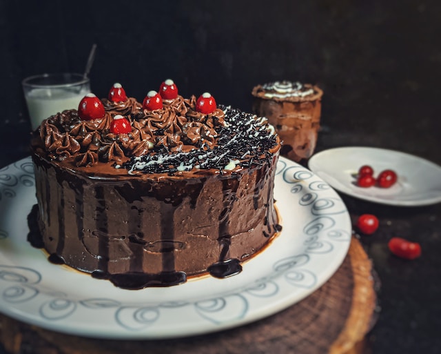 Chocolate cake topped with chocolate ganache and some cherries